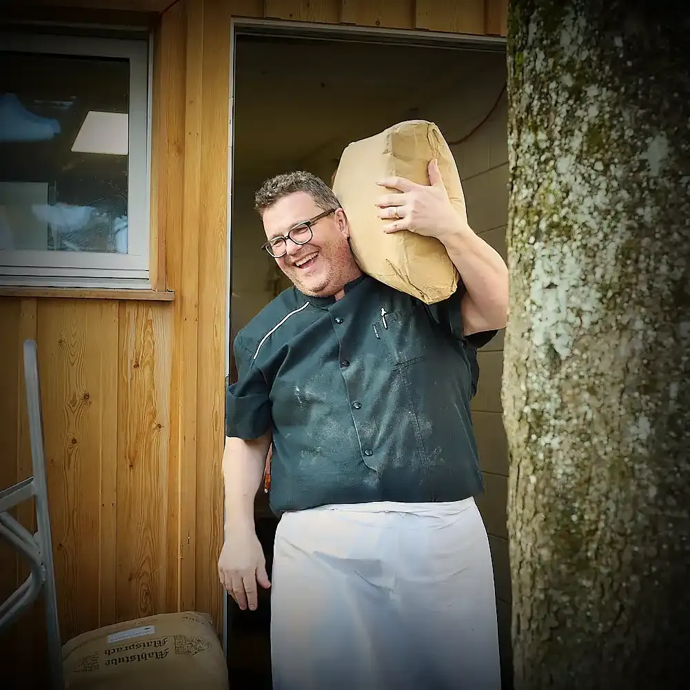 Michael Karlin trägt einen Sack Mehl aus der Backstube